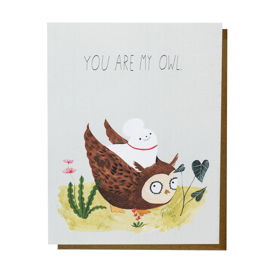 Illustrated greeting card with the text “You are my owl.” A brown owl bends forward on grassy ground with small plants and flowers surrounding, while a white dog sits on its back ready for takeoff. 